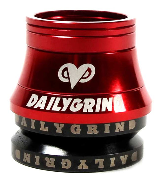 Red anodized bicycle headset with white "DAILYGRIND" branding and heart-shaped logo, showing integrated bearing cups and conical design against white background.